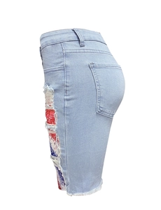 Detail of ripped light blue denim shorts with flag print patch and frayed edges