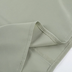 Détail du tissu satin vert clair montrant une double couture de qualité sur l'ourlet
