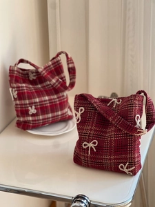 Detail view of red plaid wool armpit bags with elegant white bow embroidery textures
