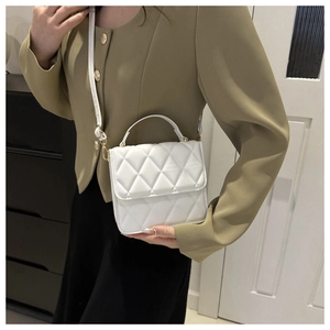 Détail du petit sac blanc matelassé avec boucles dorées et bandoulière sur le mannequin
