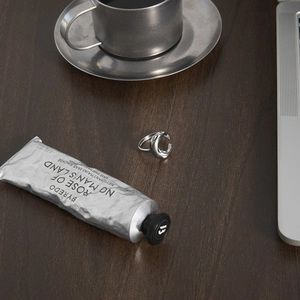 Detailed view of silver organic liquid metal rings set on a dark wooden surface