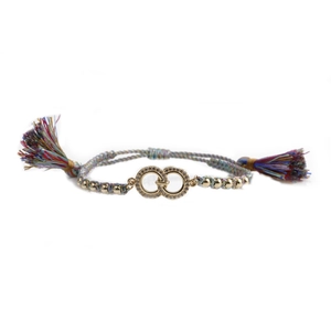 Macro detail of woven friendship bracelet with gold double rings and colorful tassels