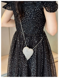 Silver heart-shaped mini evening bag with rhinestones shown on a black sequin dress