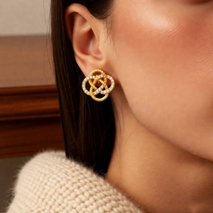 Close-up of a model wearing golden interlocking zircon stud earrings with twist texture