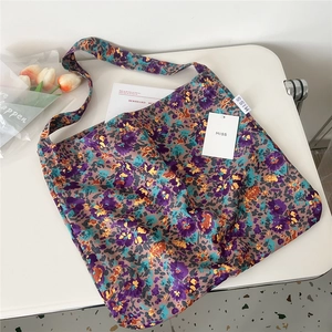 Detailed view of canvas tote bag with purple floral pattern on a lifestyle desk setup