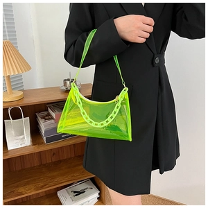 Close-up of neon green jelly bag with chunky plastic chain worn by a model in black