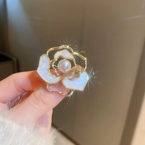 Détails macro d'une broche camélia en plaqué or avec une perle blanche centrale