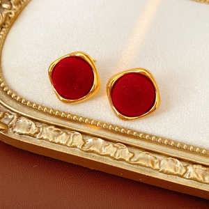 Détail de boucles d'oreilles géométriques floquées rouges avec monture dorée texturée