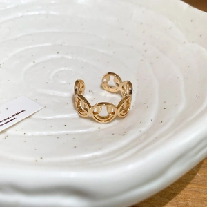 Detailed view of the gold smiley face cutout ring on a textured white ceramic tray