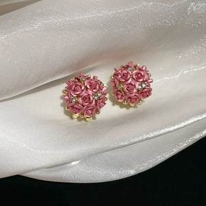 Macro shot of 3D pink rose flower stud earrings with rhinestones on silk fabric