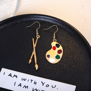 Artistic paintbrush and palette earrings in gold finish set on a black display disk