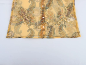 Detail of yellow paisley organza blouse hem with sheer fabric and white buttons