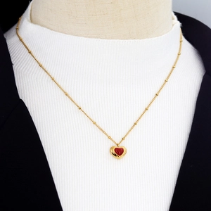 Elegant gold beaded chain necklace with red heart pendant on a stylish outfit
