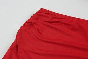 Detailed close-up of the red ruched fabric and high-quality stitching on the evening dress