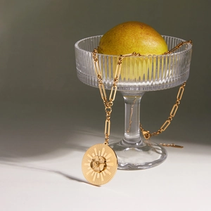 Detail of 18K gold camellia sunburst pendant on a paperclip chain with lobster clasp