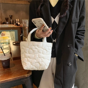 Close-up of quilted white tote bag with floral pattern texture in a cafe setting