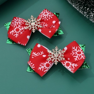Detail of red Christmas bow hair clips with white snowflake patterns and gold glitter accents