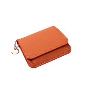 Minimalist orange lychee leather wallet with a golden round metal pendant on white background