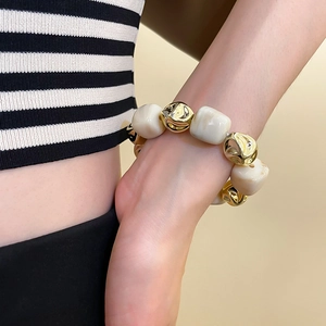 Detail of irregular gold beads and marble texture acrylic bracelet on model's wrist