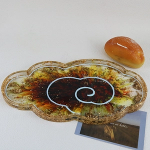 Close-up of cloud-shaped resin tray with golden flakes and artistic swirls