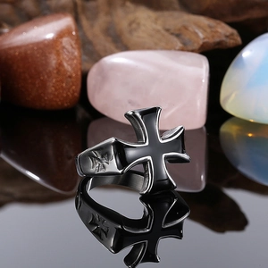 Macro shot of a black enamel Maltese cross ring on a reflective surface with minerals