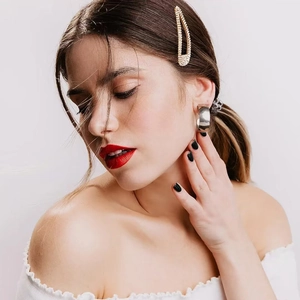 Close-up of a silver-tone metal C-hoop earring and gold-tone rhinestone hair clip on a model