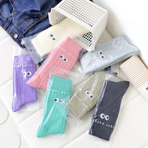 Detailed view of colorful slouch socks with embroidered eyes and Sugar Puss branding