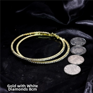 Detailed macro view of 8cm gold oversized hoop earrings featuring shiny white rhinestones