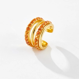 Detail of gold double-row ear cuff featuring orange zircon micro-inlay on minimalist metal