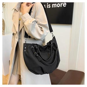 Detail of black canvas tote bag with adjustable shoulder strap shown on a model side view