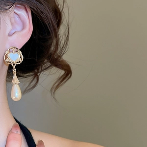 Detail of vintage heart and teardrop pearl earring worn on a model for a classic look