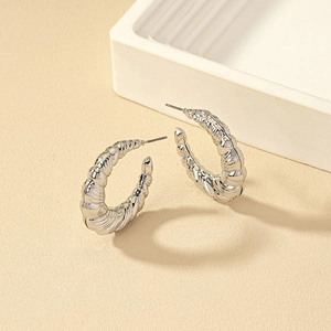 Detailed view of silver croissant C-shaped hoop earrings with twisted metal texture