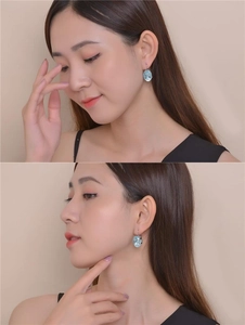 Detailed close-up of oval light blue zircon earrings worn by a model in silver finish