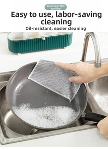 Detailed view of silver wire dishcloth cleaning a non-stick pan with soap foam