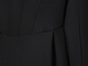 Détail du tissu noir d'une robe blazer montrant la couture fine et les plis à la taille