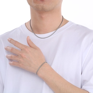 Dettaglio del set collana e bracciale in acciaio inossidabile argento su modello uomo