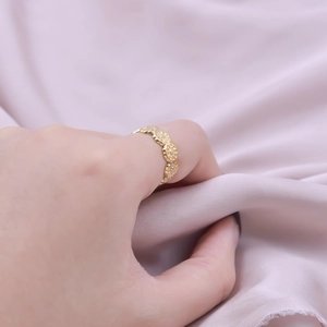 Close-up of gold stainless steel ring featuring engraved daisy floral patterns