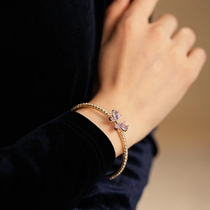 Détail d'un élégant bracelet papillon doré avec cristaux violets et oxydes de zirconium