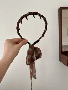 Detail of coffee brown polka dot hairband with inner non-slip teeth and chiffon ribbon