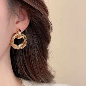 Close-up of three interlocking gold circular earrings on model for minimalist style