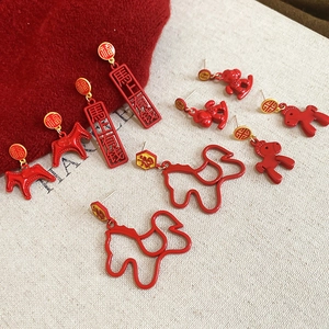 Macro shot of red enamel horse earrings with gold Chinese character charms