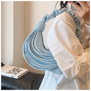 Detail of light blue pleated handbag with artistic tubular design and knotted handle