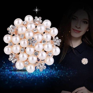 Detailed view of floral pearl brooch with clear rhinestones on a golden metal base
