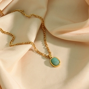 Détail du pendentif amazonite vert menthe sur chaîne dorée sur tissu de soie beige