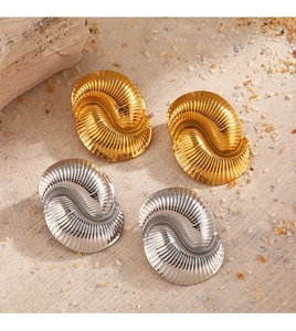 S-shaped ribbed earrings in gold and silver finish on a beach sand background