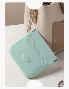 Close-up of light green bear-shaped folding mirror with metal chain for portable storage