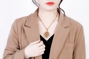 Close-up of a gold Hamsa hand pendant with rhinestone circle on a female model