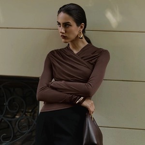 Detail of the deep brown V-neck top showing ruched fabric and elegant pleated texture