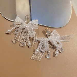 Detail of lace bow earrings with hanging pearls and crystals on leather surface