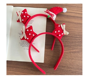 Close-up of plush red star and Christmas hat headbands with bells on a rustic wooden desk